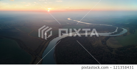 Aerial view of wide river flowing quietly in rural countryside in autumn evening 121358431
