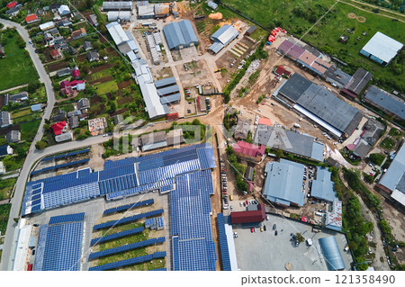 Aerial view of solar power plant with blue photovoltaic panels mounted on industrial building roof for producing green ecological electricity. Production of sustainable energy concept. 121358490