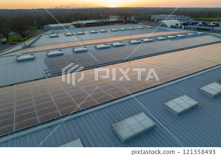 Aerial view of solar power plant with blue photovoltaic panels mounted on industrial building roof for producing green ecological electricity. Production of sustainable energy concept Aerial view of solar power plant with blue photovoltaic panels mounted on industrial building roof for producing green ecological electricity. Production of sustainable energy concept 121358493