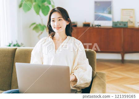 Woman using a computer on the sofa Woman using a computer on the sofa 121359165