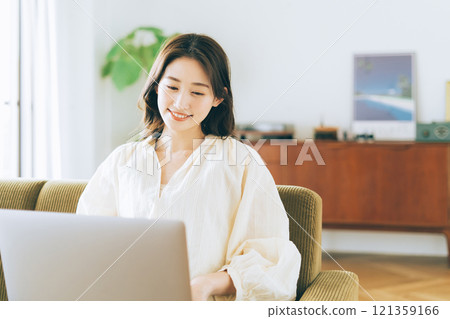 Woman using a computer on the sofa 121359166