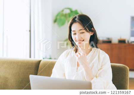 Woman using a computer on the sofa 121359167