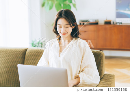 一個女人在沙發上使用電腦 121359168