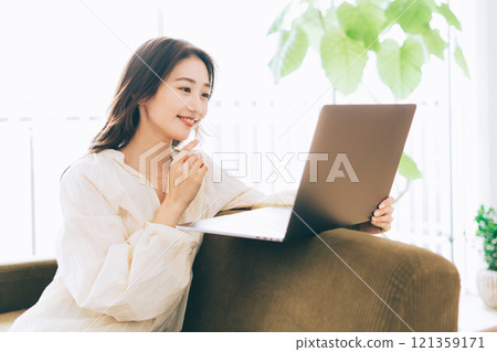 一個女人在沙發上使用電腦 121359171