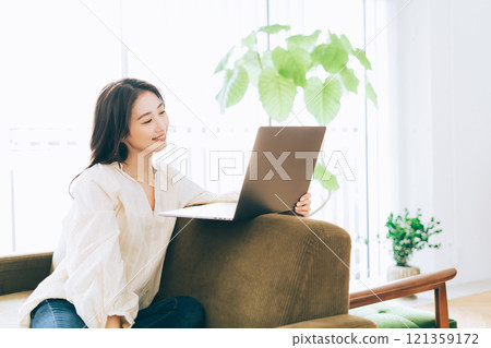 一個女人在沙發上使用電腦 121359172