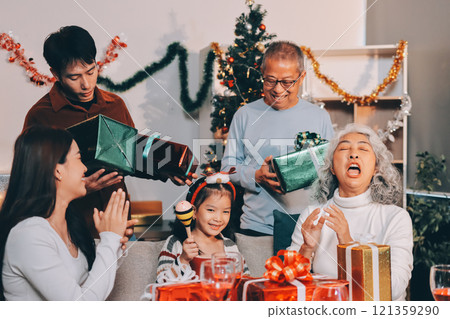 Portrait of Asian family exchanging presents during christmas at home. Attractive happy people holding gift box, celebrate holiday thanksgiving, xmas eve tradition in living room in house together. Portrait of Asian family exchanging presents during christmas at home. Attractive happy people holding gift box, celebrate holiday thanksgiving, xmas eve tradition in living room in house together. 121359290
