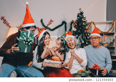 Portrait of Asian family exchanging presents during christmas at home. Attractive happy people holding gift box, celebrate holiday thanksgiving, xmas eve tradition in living room in house together. Portrait of Asian family exchanging presents during christmas at home. Attractive happy people holding gift box, celebrate holiday thanksgiving, xmas eve tradition in living room in house together. 121359303