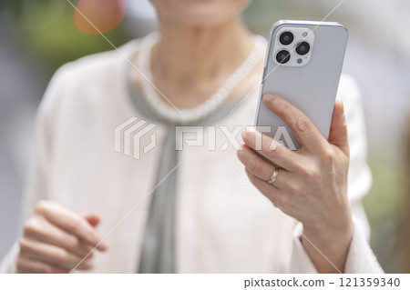 拿著智慧型手機的資深婦女的手 121359340