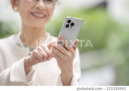 Senior woman's hand operating a smartphone 121359341