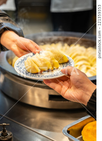 Customer receives a plate of pot stickers from the waiter 121359353