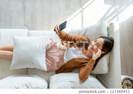 High angle view of happy cheerful positive young Asian woman on the phone at home 121360451