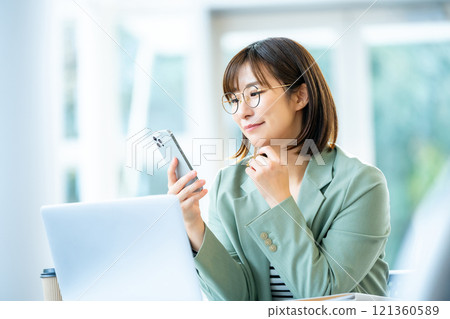 A woman operating a smartphone A female employee using a smartphone 121360589