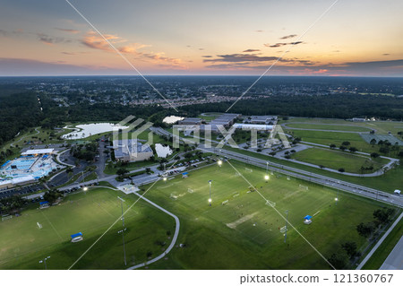 Aerial view of public sports park with people engaged in football game on grass stadium at sunset. Active way of life concept 121360767