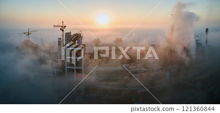 Aerial view of cement factory with high concrete plant structure and tower crane at industrial manufacturing site on foggy evening. Production and global industry concept. Aerial view of cement factory with high concrete plant structure and tower crane at industrial manufacturing site on foggy evening. Production and global industry concept. 121360844