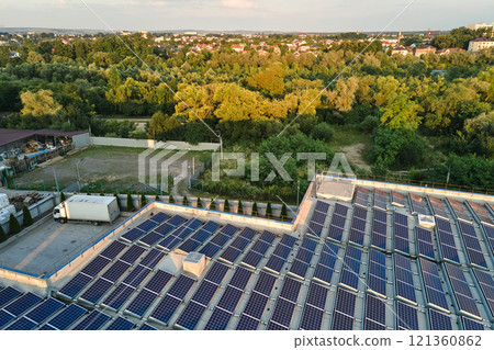 Aerial view of blue photovoltaic solar panels mounted on industrial building roof for producing green ecological electricity. Production of sustainable energy concept Aerial view of blue photovoltaic solar panels mounted on industrial building roof for producing green ecological electricity. Production of sustainable energy concept 121360862