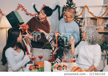 Portrait of Asian family exchanging presents during christmas at home. Attractive happy people holding gift box, celebrate holiday thanksgiving, xmas eve tradition in living room in house together. Portrait of Asian family exchanging presents during christmas at home. Attractive happy people holding gift box, celebrate holiday thanksgiving, xmas eve tradition in living room in house together. 121362102