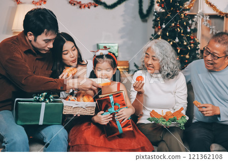 Portrait of Asian family exchanging presents during christmas at home. Attractive happy people holding gift box, celebrate holiday thanksgiving, xmas eve tradition in living room in house together. Portrait of Asian family exchanging presents during christmas at home. Attractive happy people holding gift box, celebrate holiday thanksgiving, xmas eve tradition in living room in house together. 121362108