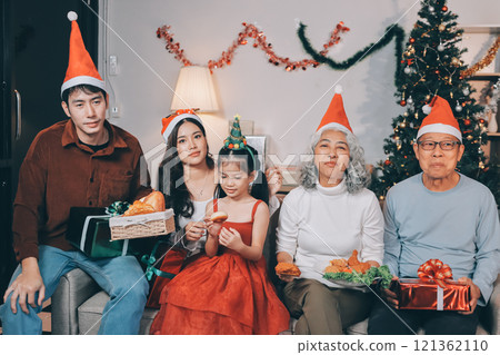 Portrait of Asian family exchanging presents during christmas at home. Attractive happy people holding gift box, celebrate holiday thanksgiving, xmas eve tradition in living room in house together. Portrait of Asian family exchanging presents during christmas at home. Attractive happy people holding gift box, celebrate holiday thanksgiving, xmas eve tradition in living room in house together. 121362110
