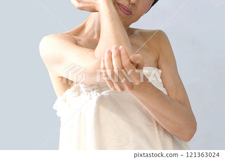 Middle-aged Asian woman holding her elbow/arm Middle-aged Asian woman holding her elbow/arm 121363024