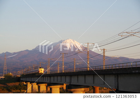 JNR彩色381系列特快八雲復興塗裝車輛行駛在日野川大橋上，駛向白雪皚皚的富士山腳下的場景。 121363053