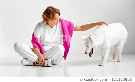 Woman Petting White Husky in Bright Pink Blanket 121363998