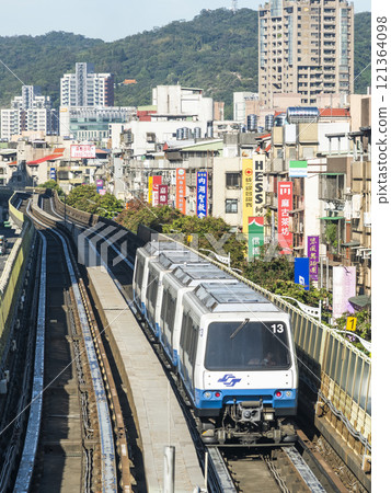 View of a Wenhu or Brown line train running on the elevated track of the Taipei Mass Rapid Transit System with the building background. 121364098