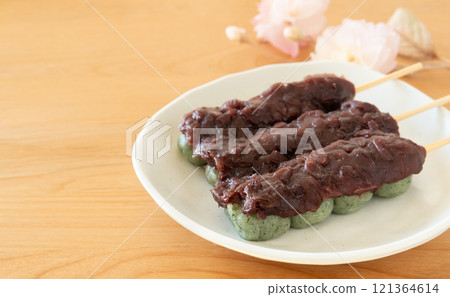 Three mugwort dumplings with bean paste and a cherry blossom - Japanese sweets 121364614