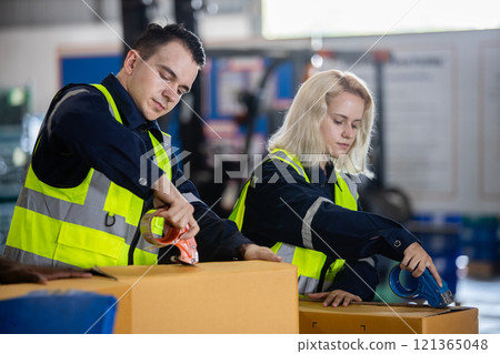 Male and female professional worker wearing safety uniform using packing tape on packaging cardboard box product in warehouse. 121365048