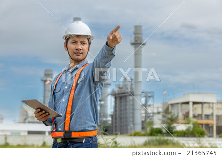 Asian worker power plant factory holding tablet pointing check construction plan power plant. Engineer wearing safety uniform helmet at energy petrochemical industry. 121365745