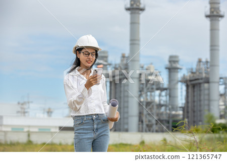 Engineer use smartphone with blueprint working factory producing electricity oil energy. Construction manager oil refinery in petrochemical. improvement inspector Industrial worker working power plant 121365747