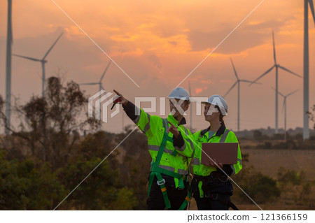 Team engineer wearing safety uniform holding laptop discussed plan about renewable energy at station energy power wind in evening when sunset. Technology environment reduce global warming problems. Team engineer wearing safety uniform holding laptop discussed plan about renewable energy at station energy power wind in evening when sunset. Technology environment reduce global warming problems. 121366159