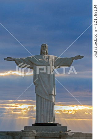 Majestic Christ the Redeemer statue in Rio de Janeiro with dramatic sky and sun rays in the background 121368134