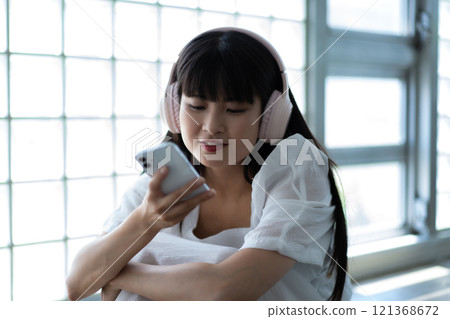 年輕女子戴著耳機在智慧型手機上聽音樂 121368672