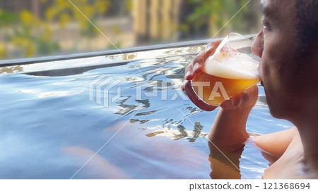 Profile of a man drinking draft beer while soaking in an open-air bath 121368694