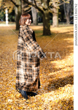 一位留著短鮑勃的年輕女子正在欣賞秋葉 121368742