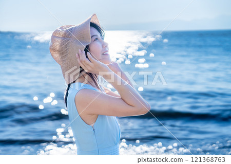 一個戴草帽的女人在海裡清爽 121368763
