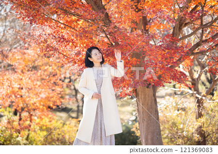 一位中年婦女在秋葉滿布的公園漫步 121369083
