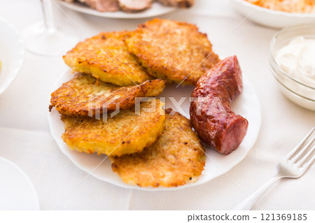 Potato pancakes with fried sausage on white plate 121369185
