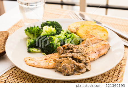 Fried river trout fillet with a complex side dish of broccoli, baked potatoes and mushroom sauce Fried river trout fillet with a complex side dish of broccoli, baked potatoes and mushroom sauce 121369193