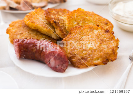 Potato pancakes with fried sausage on white plate Potato pancakes with fried sausage on white plate 121369197