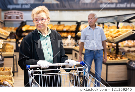 Older european woman with glasses shopping in bread section of supermarket Older european woman with glasses shopping in bread section of supermarket 121369240