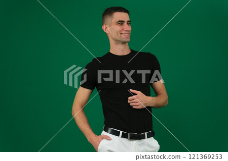 Handsome young man on grey background looking at camera. Portrait of laughing young man with hands in pockets leaning against grey wall. Happy guy smiling. Handsome young man on grey background looking at camera. Portrait of laughing young man with hands in pockets leaning against grey wall. Happy guy smiling. 121369253