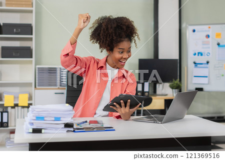 Overjoyed charming excited black woman business woman worker using smartphone and laptop working in office, feeling happy. Overjoyed charming excited black woman business woman worker using smartphone and laptop working in office, feeling happy. 121369516