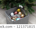 a box of Christmas decorations near a decorated Christmas tree 121371815