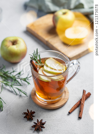 Homemade apple punch with apples, cinnamon and rosemary in a cup on a light  background 121373078