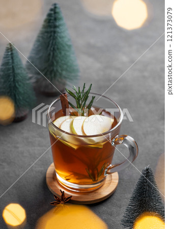 Homemade apple punch with fresh apples, cinnamon and rosemary in a cup on a dark background 121373079