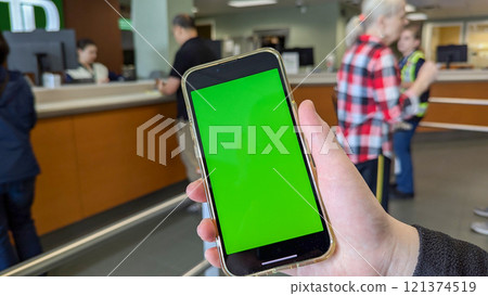 Motion of woman holding green screen phone on waiting line for service inside of TD bank. 121374519