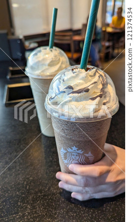 Refreshing Moments at Starbucks: Woman Grabbing a Frappuccino from Table Refreshing Moments at Starbucks: Woman Grabbing a Frappuccino from Table 121374534