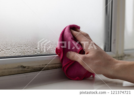 A man wipes the condensate from the window glass. Closeup. A man wipes the condensate from the window glass. Closeup. 121374721