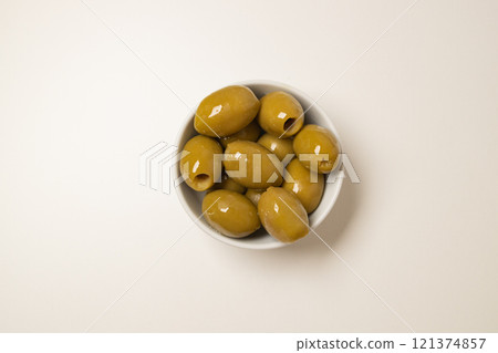 Whole green olives in white bowl on black background. Top view, close-up 121374857